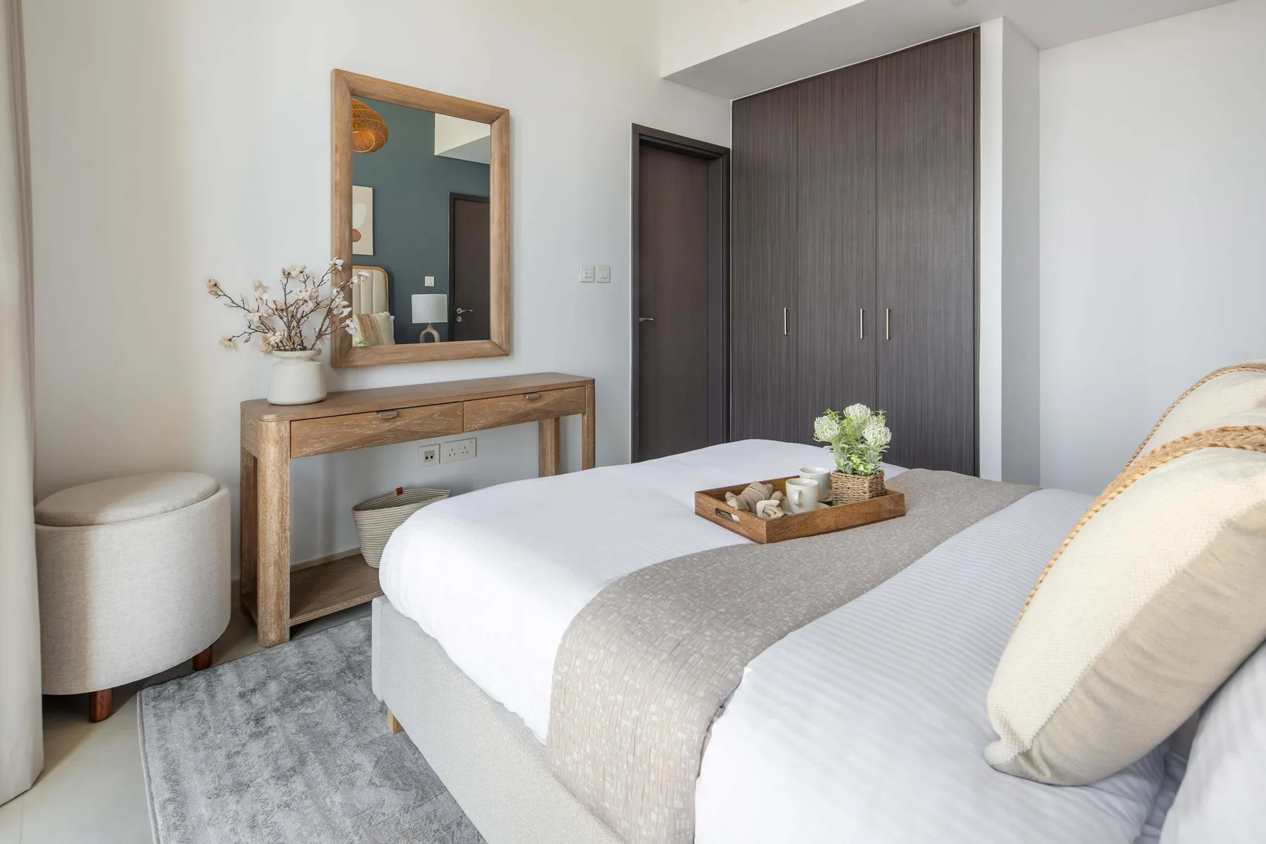 A bedroom with a bed, wooden vanity, and dark wardrobe.