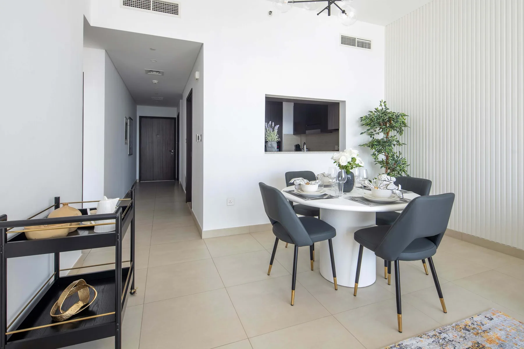 A bright dining area with a round table and dark upholstered seating.
