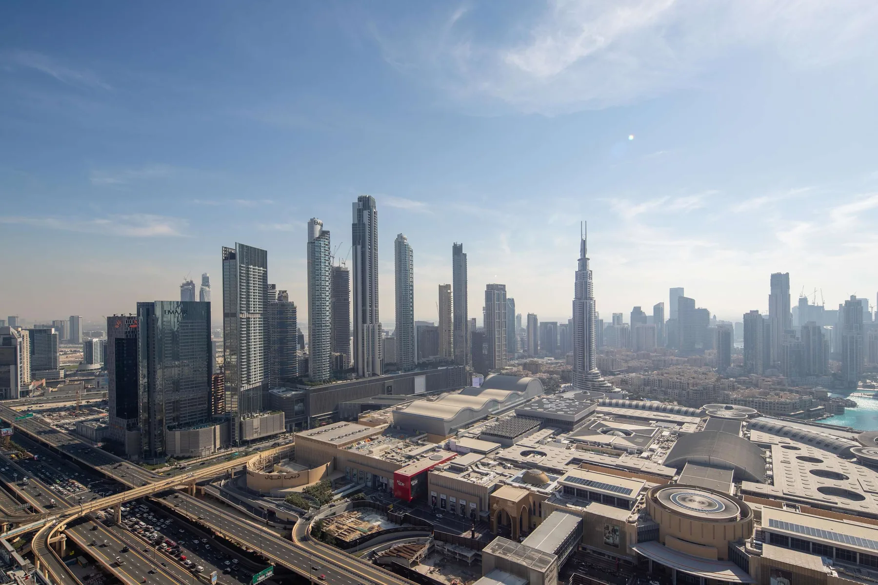A broad city skyline rises above highways and large rooftops.