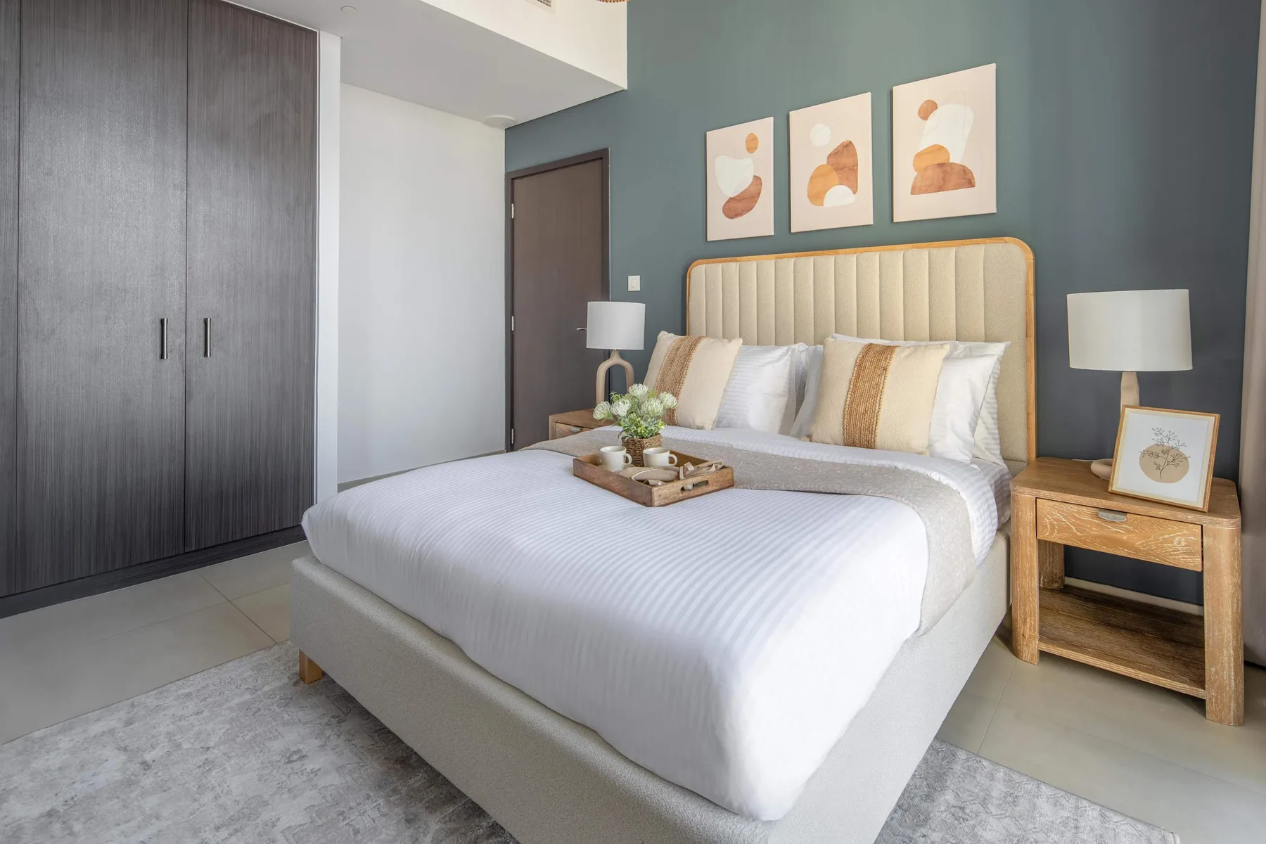 A bedroom with a neatly made bed and framed artwork above the headboard.