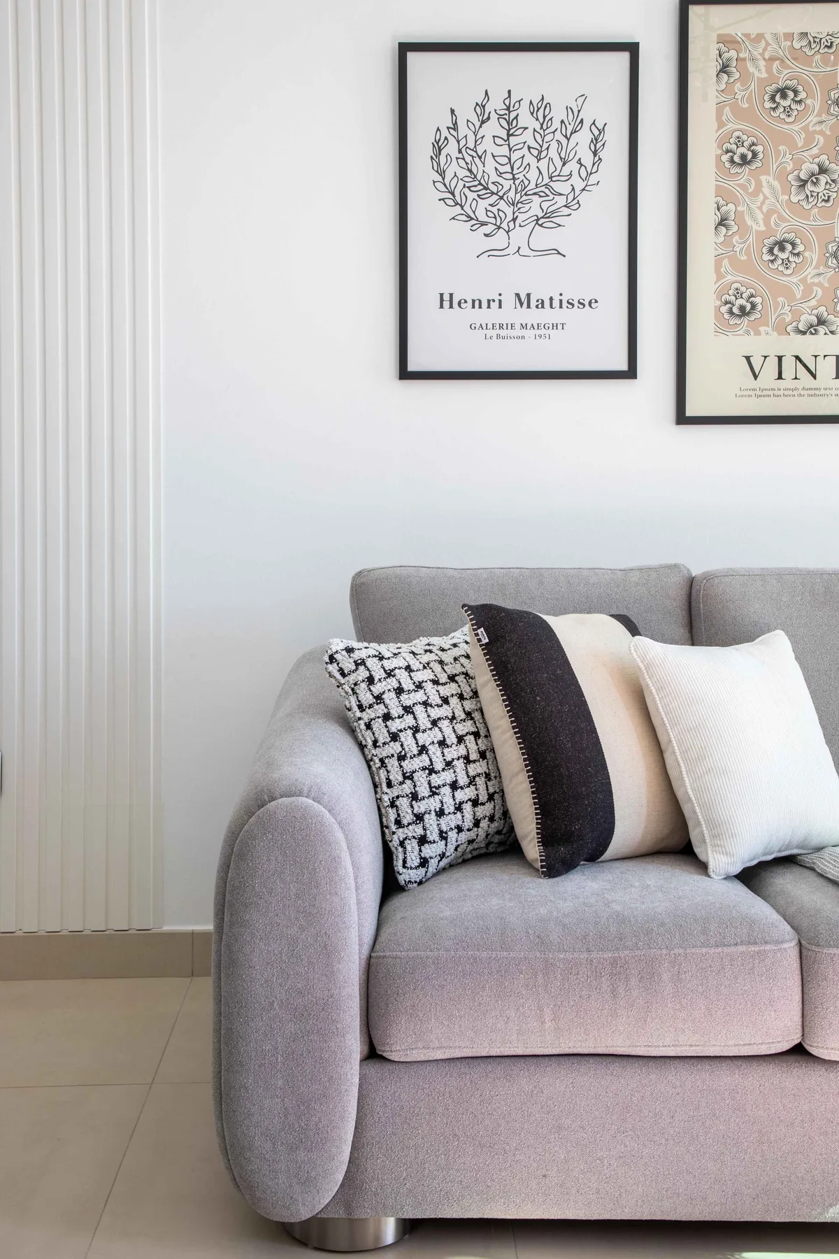 A gray sofa with patterned cushions sits beneath framed wall art.