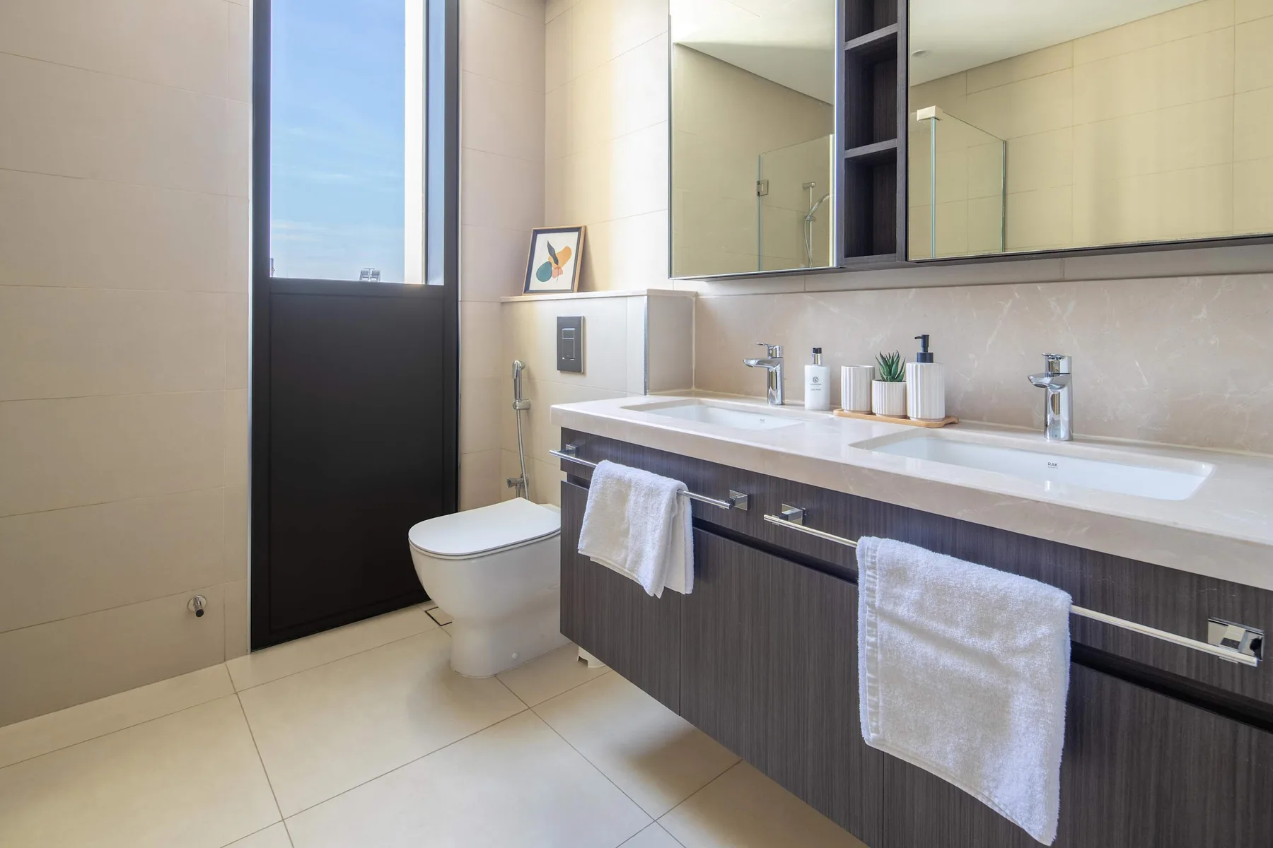 A modern bathroom with a long vanity, mirrors, and a shower.