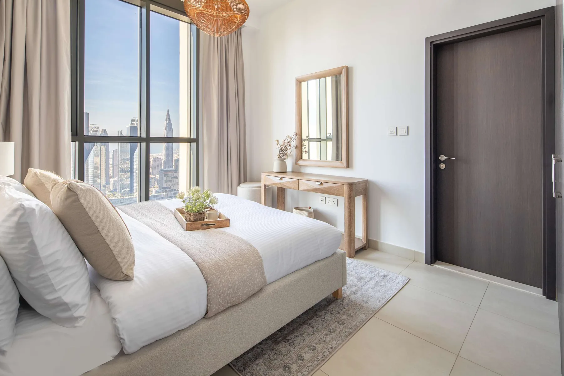 A bright bedroom with a neatly made bed beside a large window.