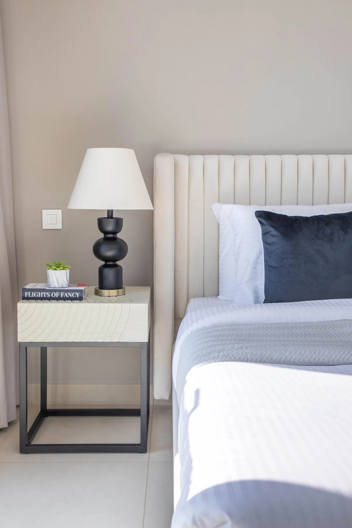Bedroom with a neatly made bed beside a bedside table and lamp.
