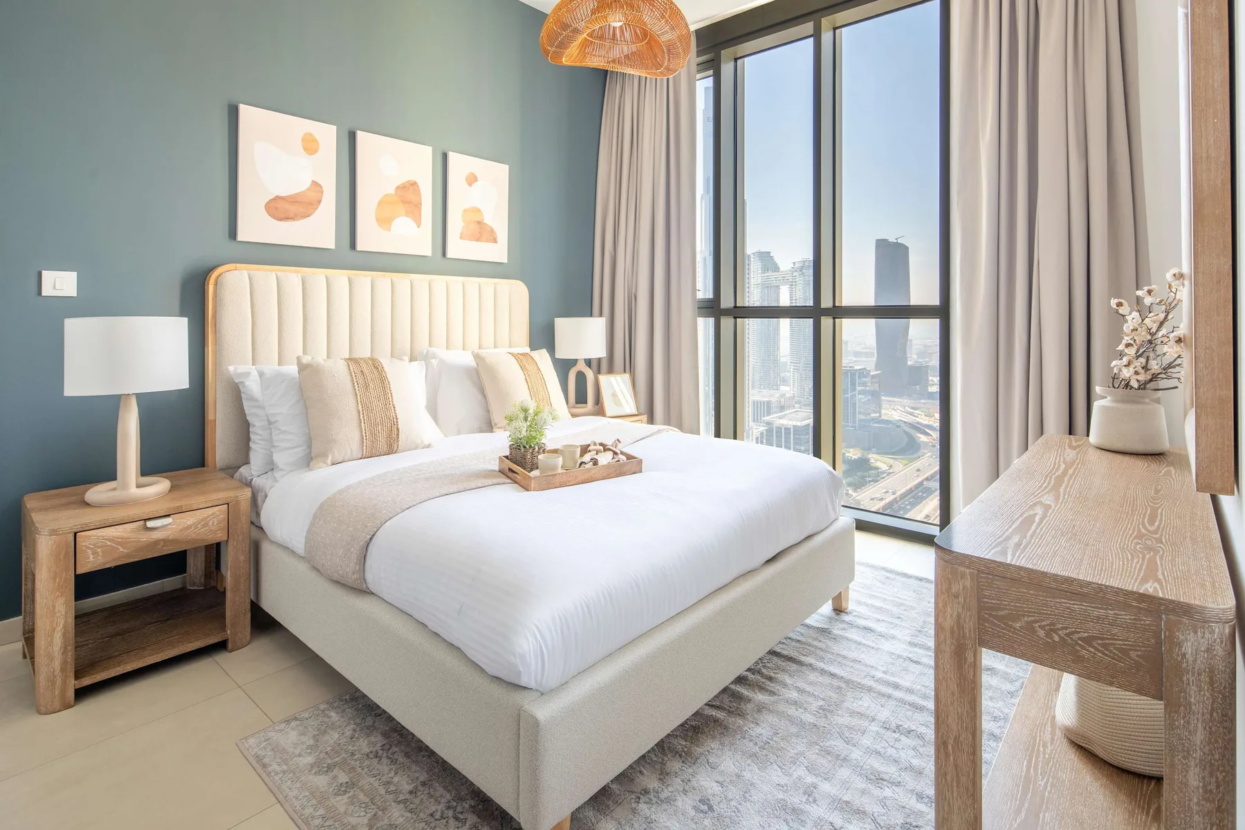 A bedroom with a neatly made bed, bedside tables, and large windows.