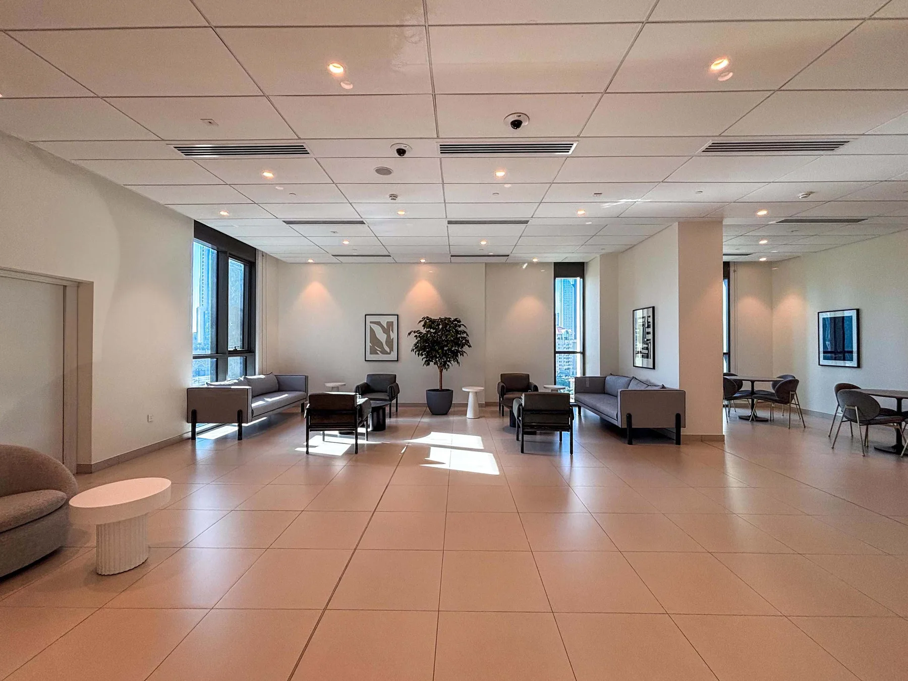 A spacious lounge with seating, framed artwork, and large windows.