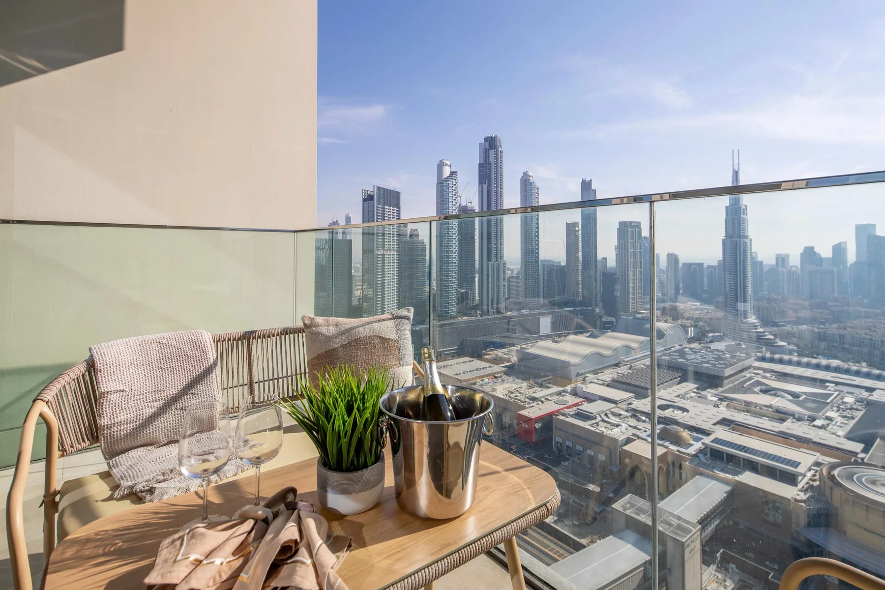 A balcony seating area overlooks a city skyline beyond a glass railing.