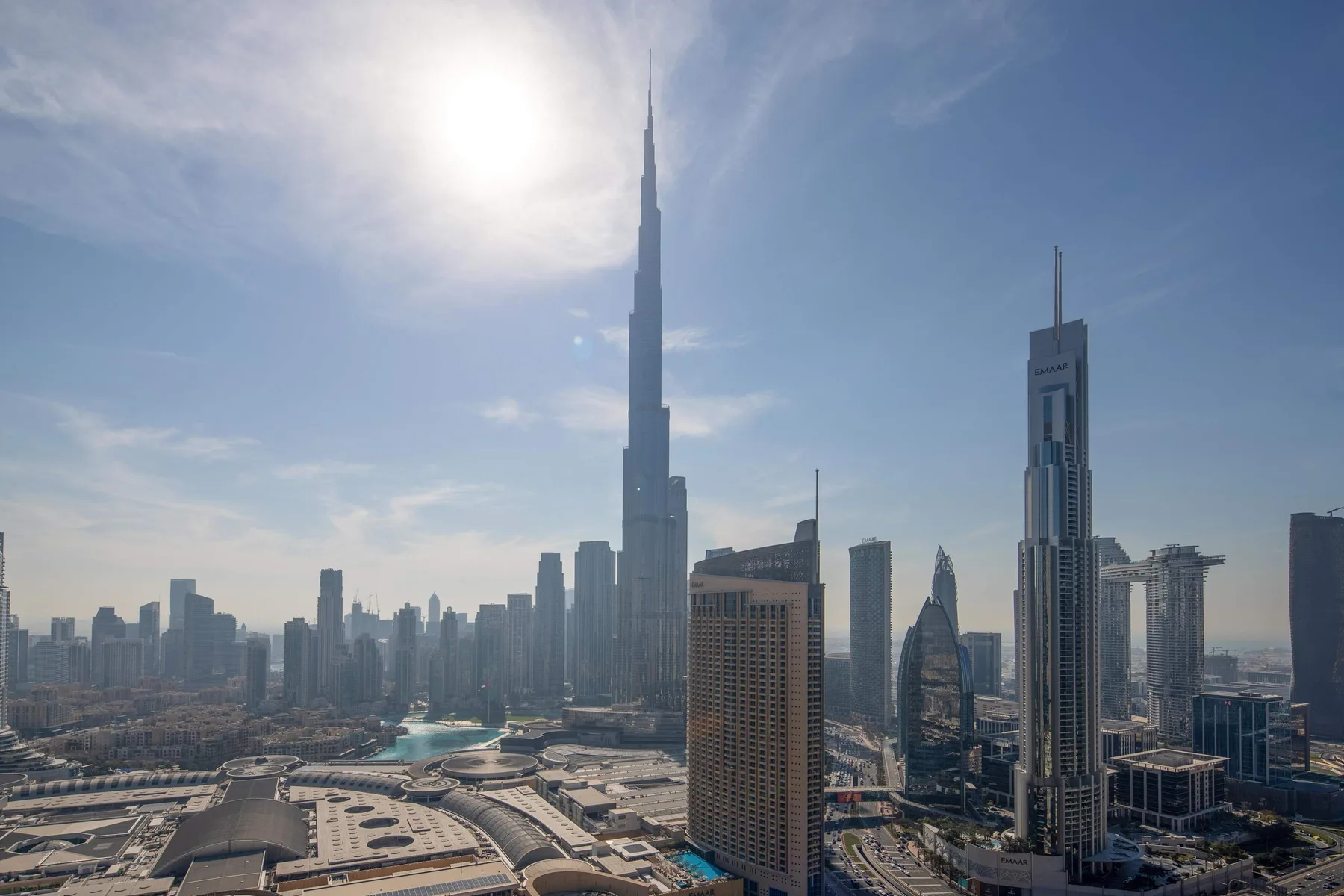 A city skyline with a very tall central skyscraper beneath a bright, hazy sky.