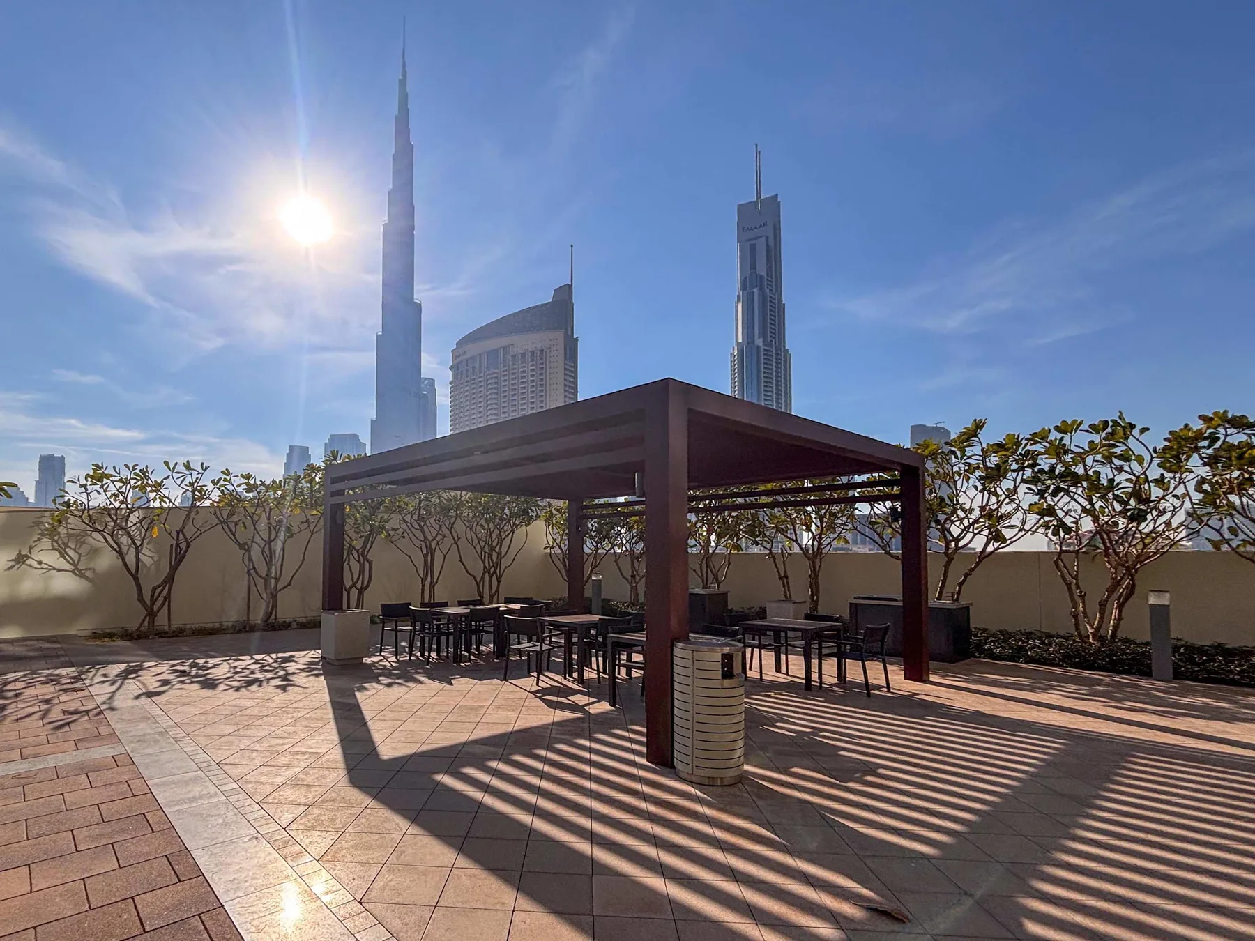 A rooftop terrace with a shaded seating area and city skyscrapers in the background.