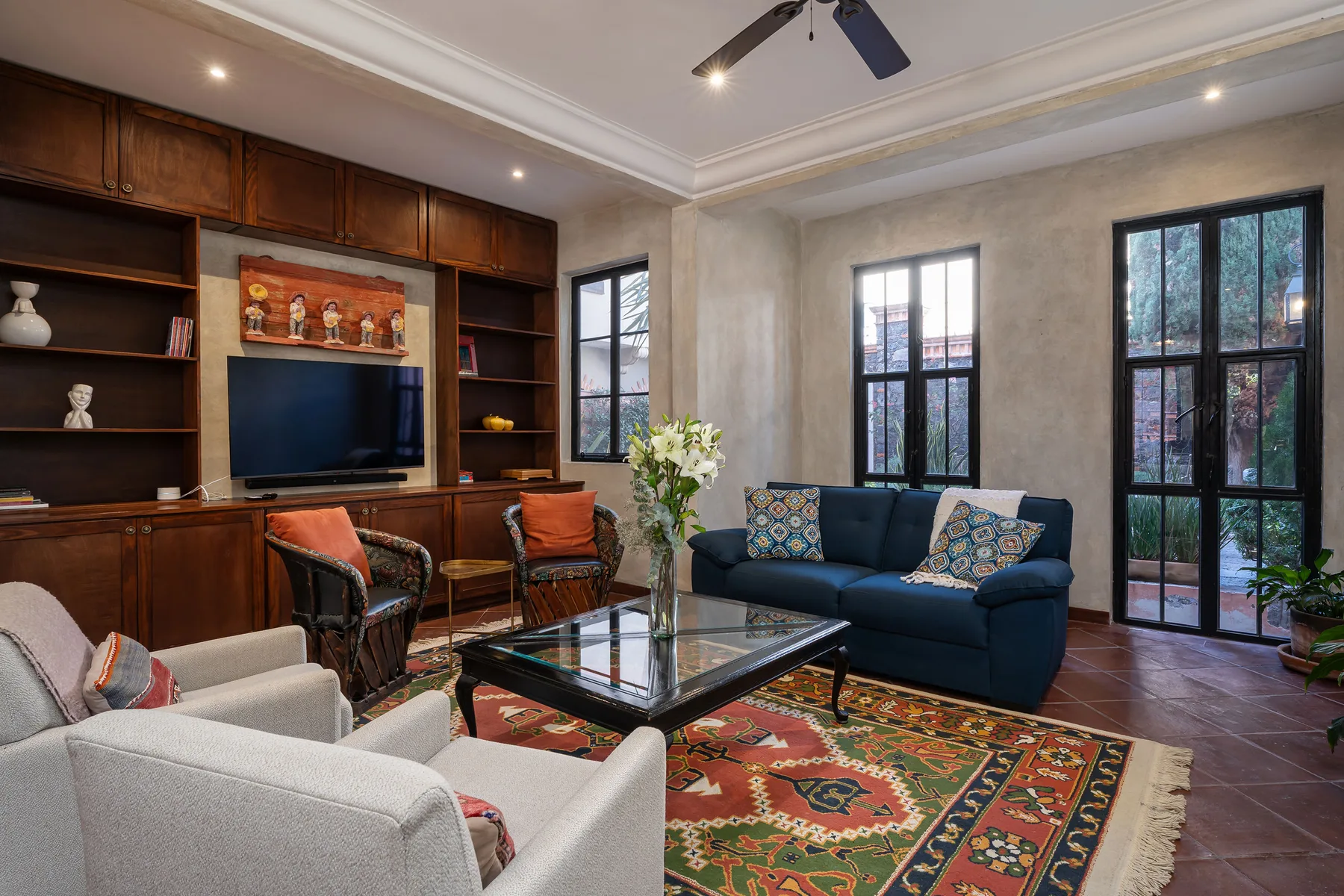A living room with seating around a glass coffee table and colorful rug.