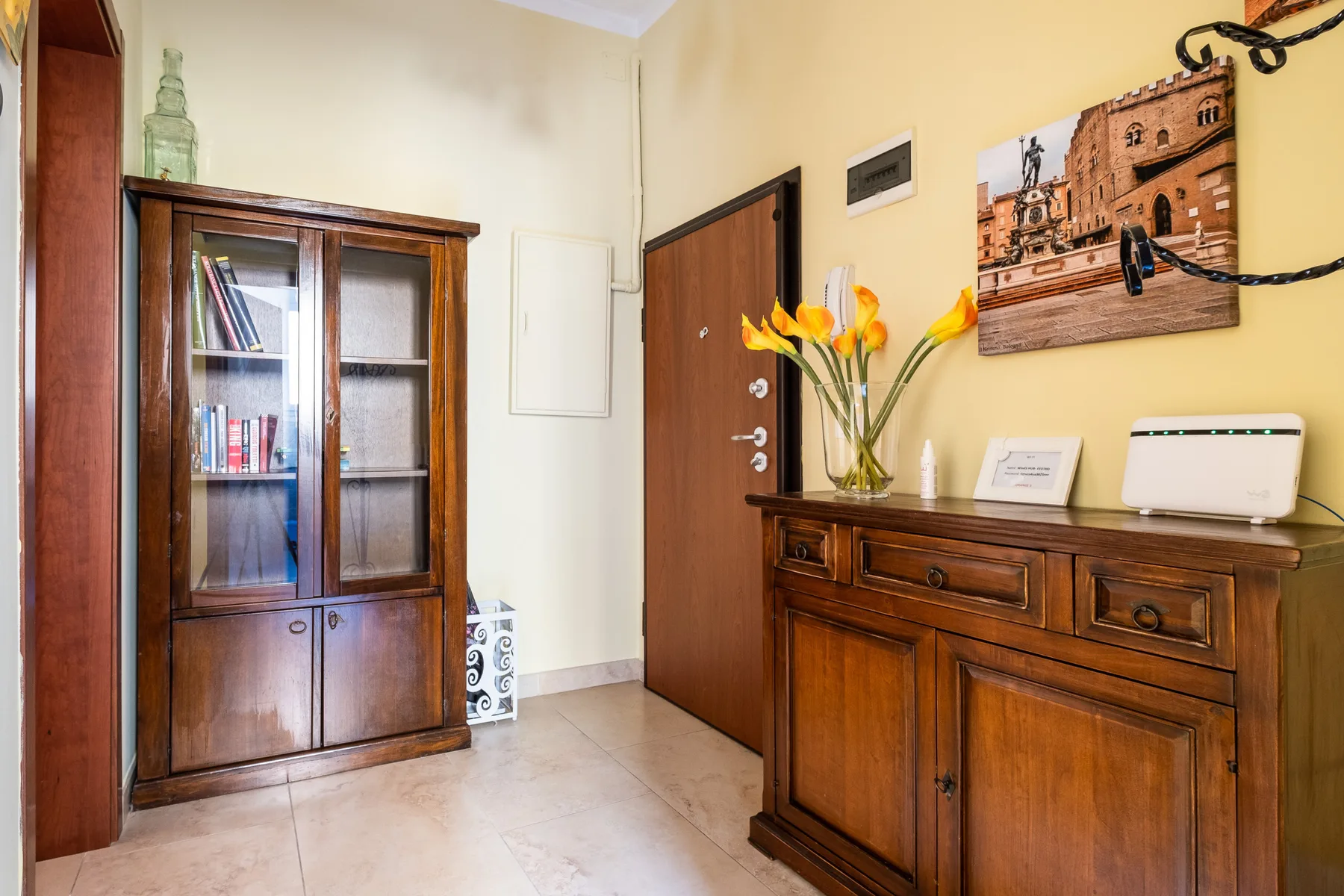 Un recibidor de tonos cálidos con muebles de madera y un jarrón con flores.