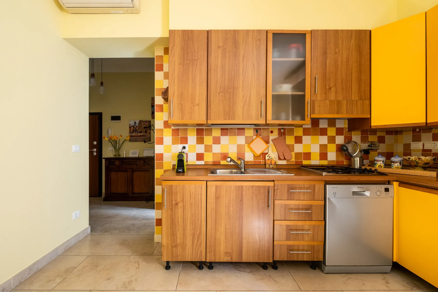 Una cocina con armarios de madera, un salpicadero de azulejos y un lavavajillas de acero inoxidable.