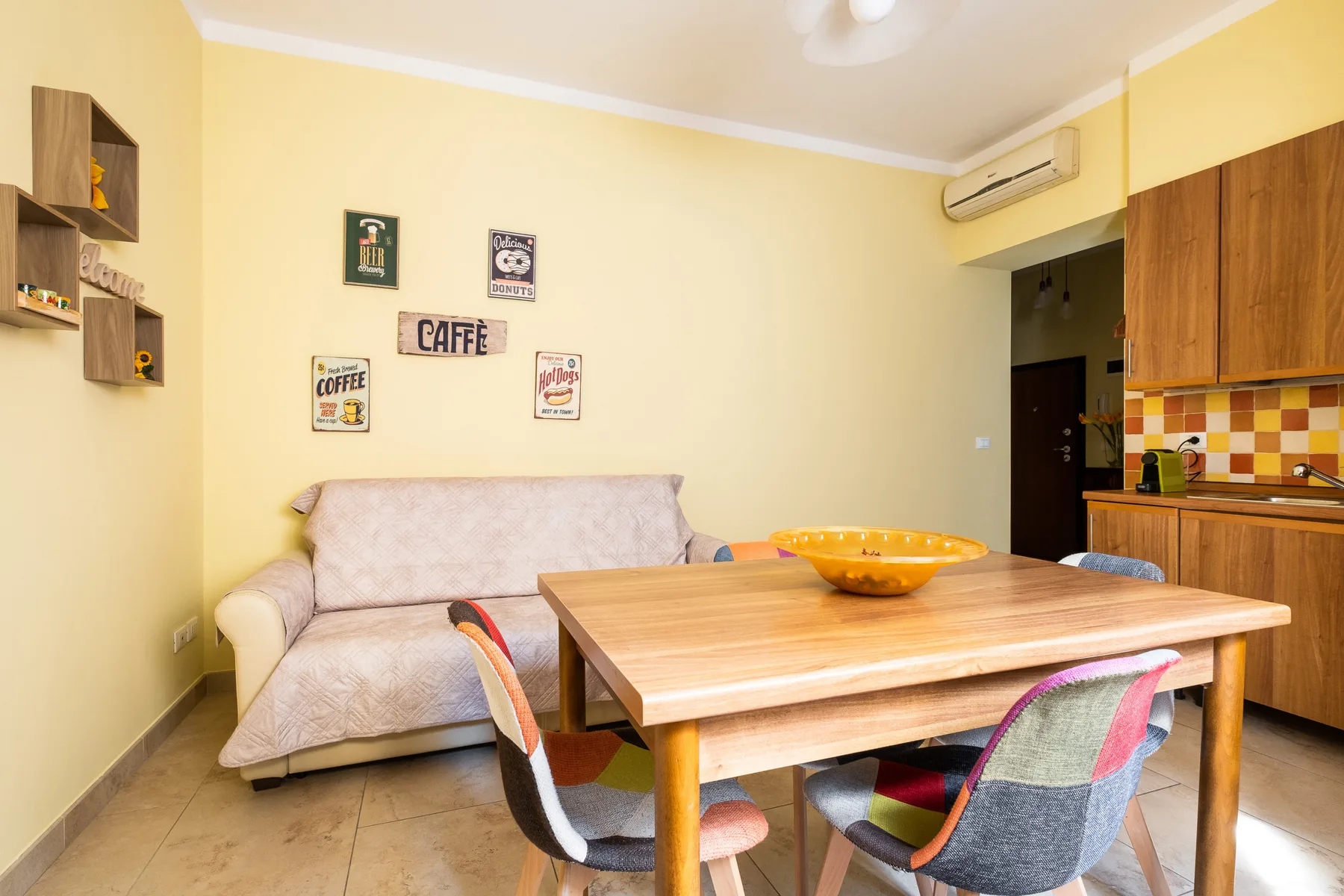 Un comedor con una mesa de madera y asientos junto a un sofá.