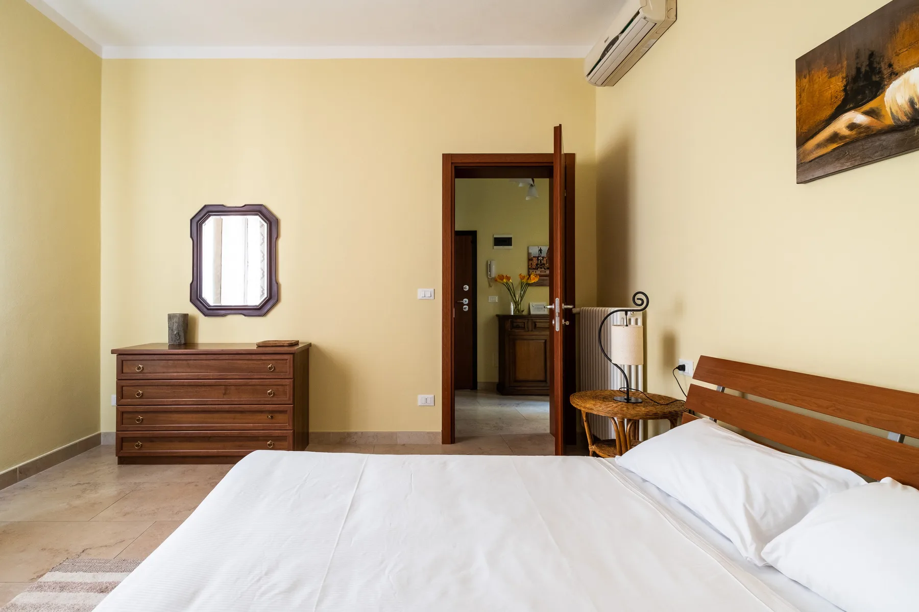 Un dormitorio con una cama, una cómoda de madera y una puerta abierta.
