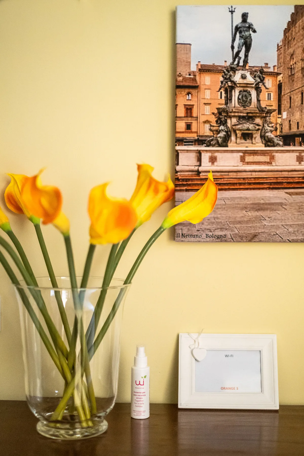 Un conjunto sobre una mesa con flores amarillas, una fotografía enmarcada y un frasco pequeño.