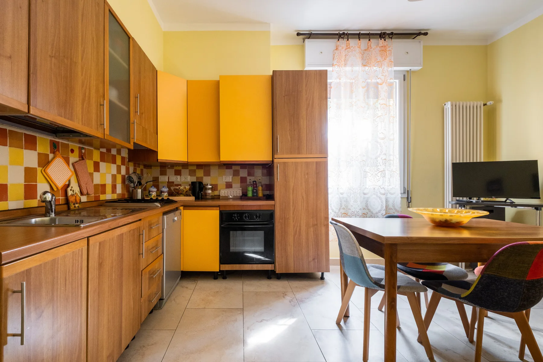 Una cocina y comedor con armarios de madera y una mesa junto a la ventana.