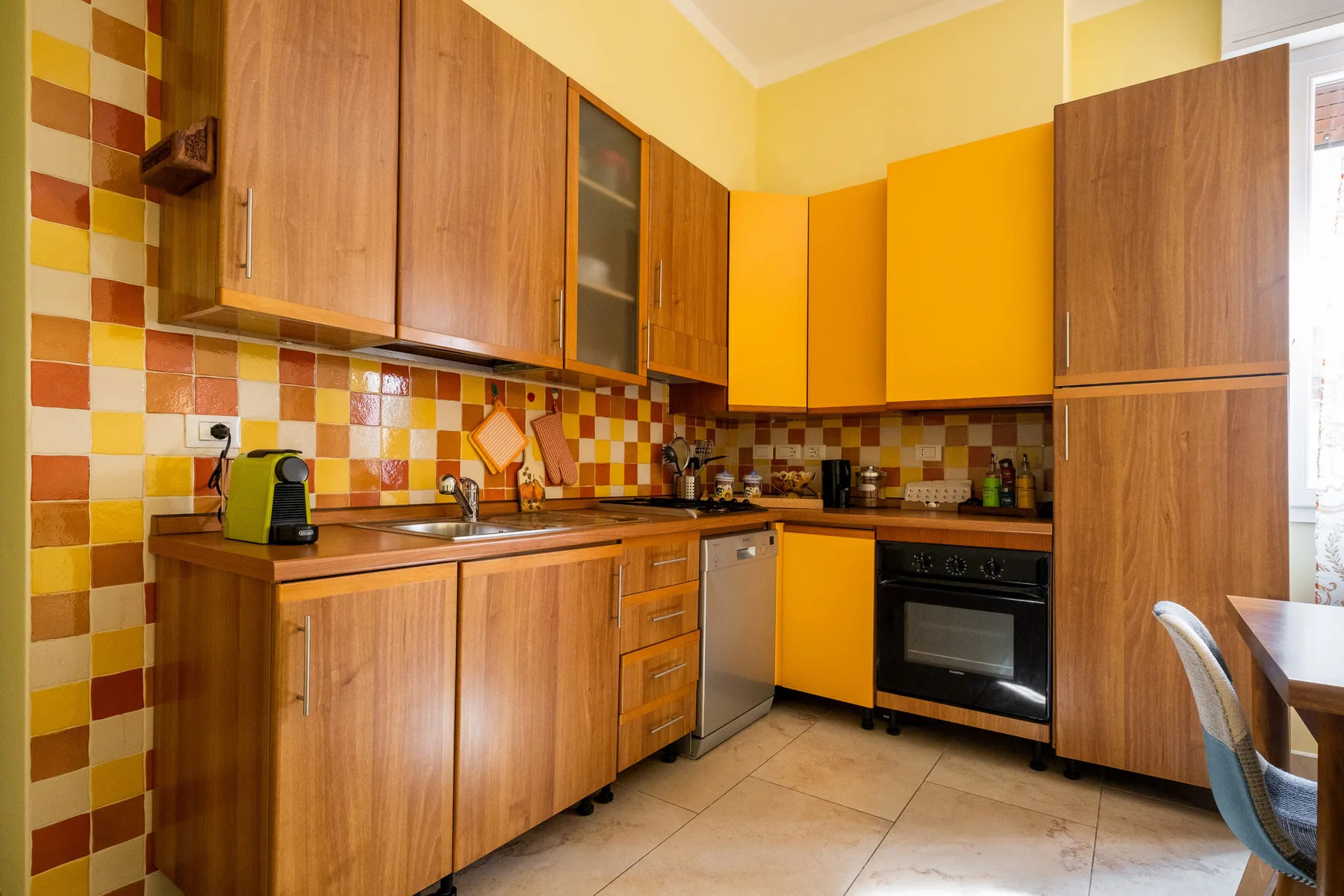 Una cocina con gabinetes de madera, armarios amarillos y un salpicadero de azulejos.