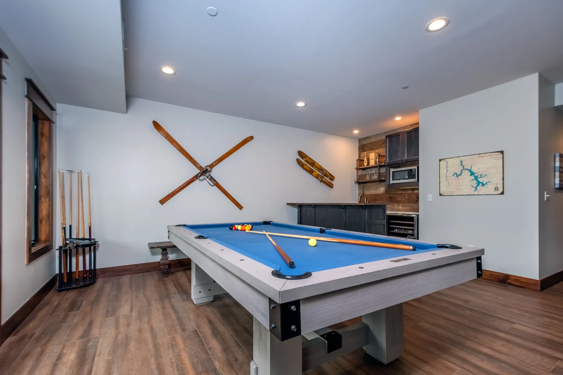 A game room with a blue pool table and crossed wooden paddles on the wall.