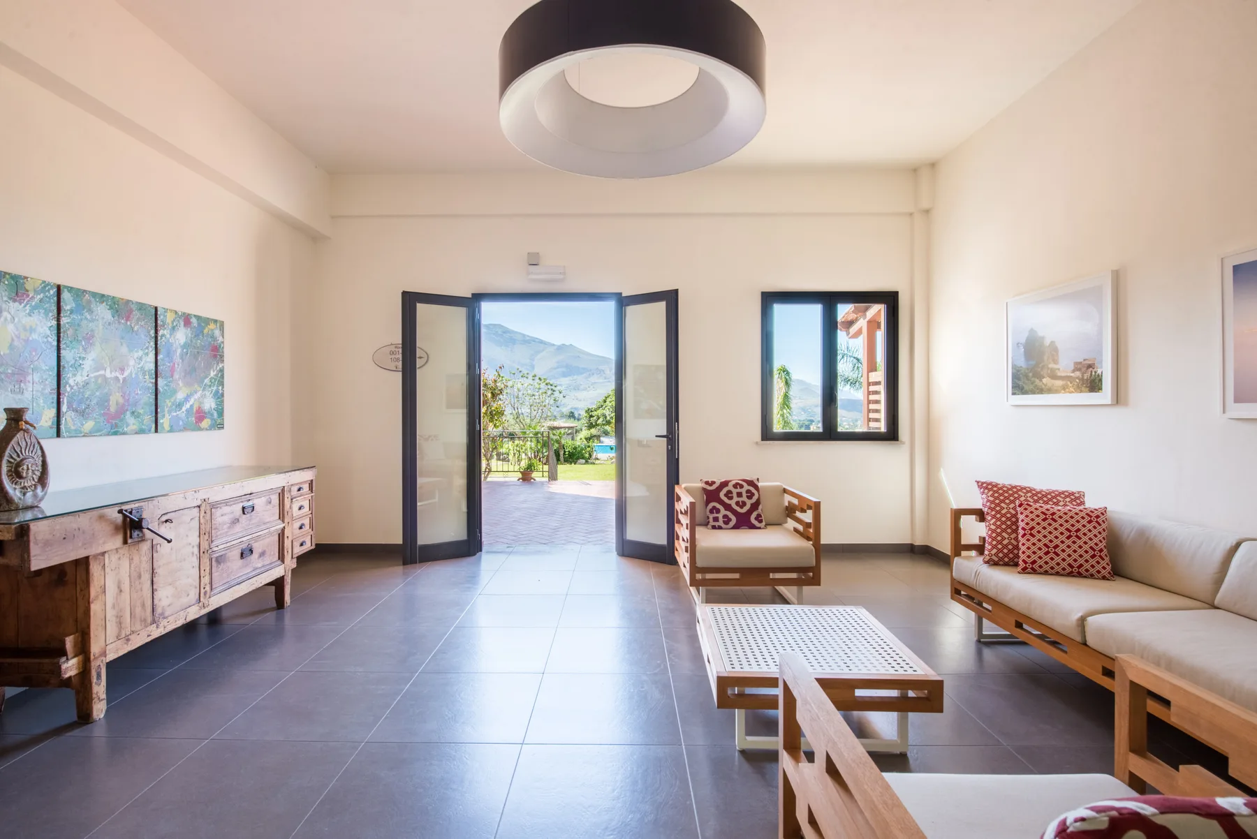 A bright living room with seating and an open doorway to a garden.