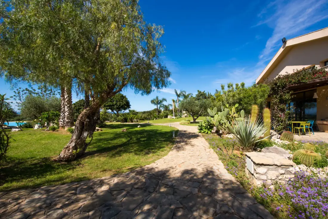 A stone path winds through a landscaped garden beside a building.