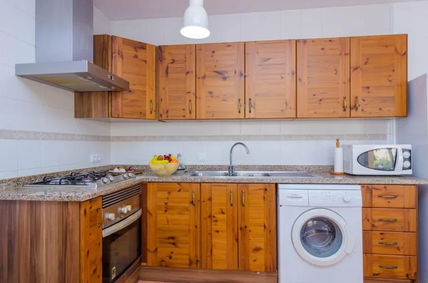 A kitchen with wooden cabinets, a countertop, and a washing machine.