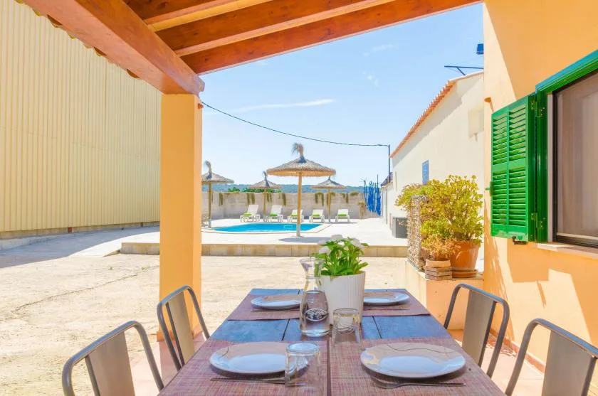 A shaded outdoor dining area overlooks a swimming pool and patio.