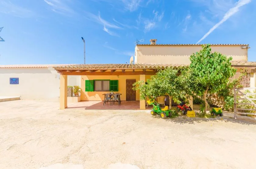A house with a shaded patio and trees in the courtyard.