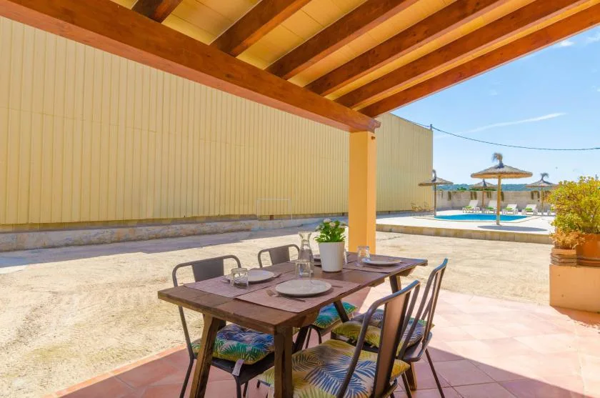 A shaded outdoor dining area with a table and seating beside an open courtyard.