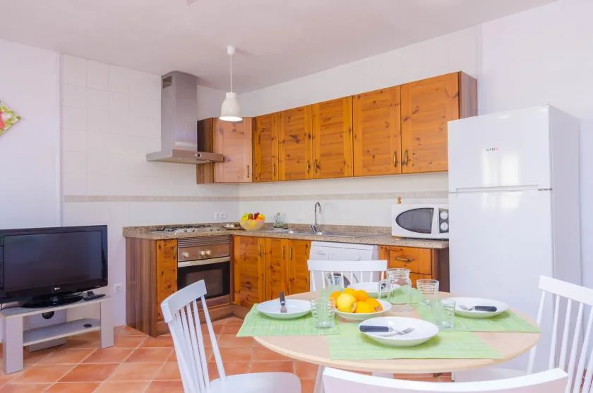 A bright kitchen and dining area with wooden cabinets and a round table.