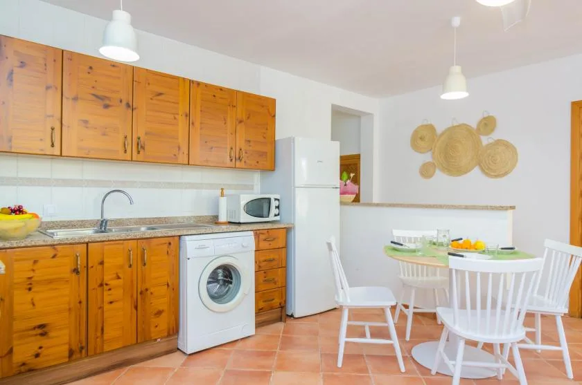 A kitchen and dining area with wooden cabinets, a refrigerator, and a table.