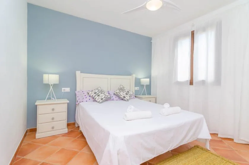 A bedroom with a white bed, bedside tables, and a blue accent wall.