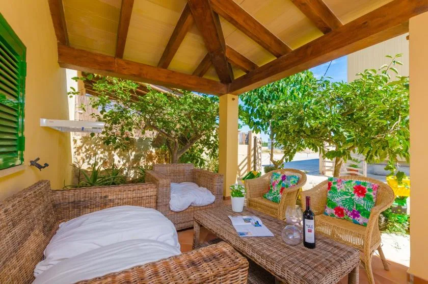 A covered outdoor seating area with woven furniture and colorful cushions.