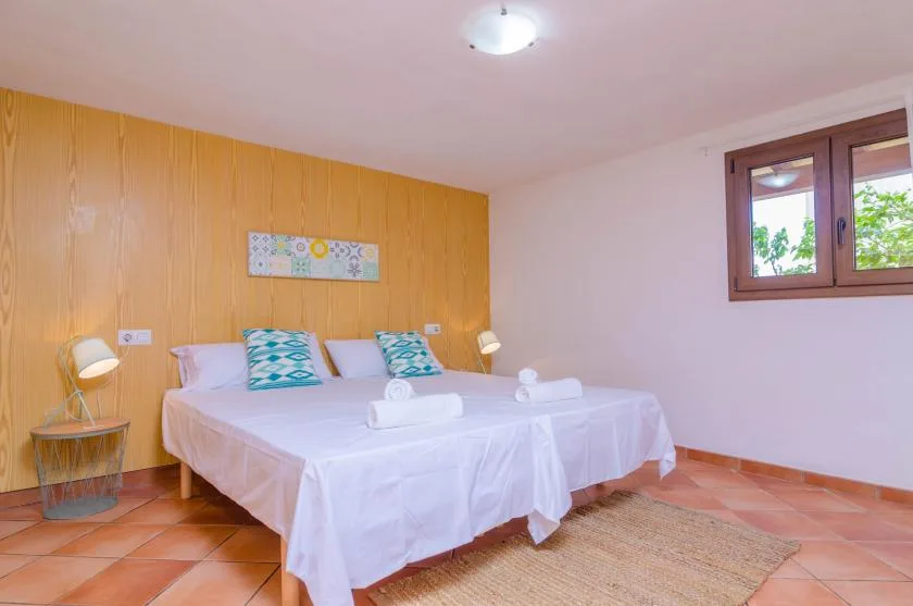 A bedroom with white bedding, patterned pillows, and a window.