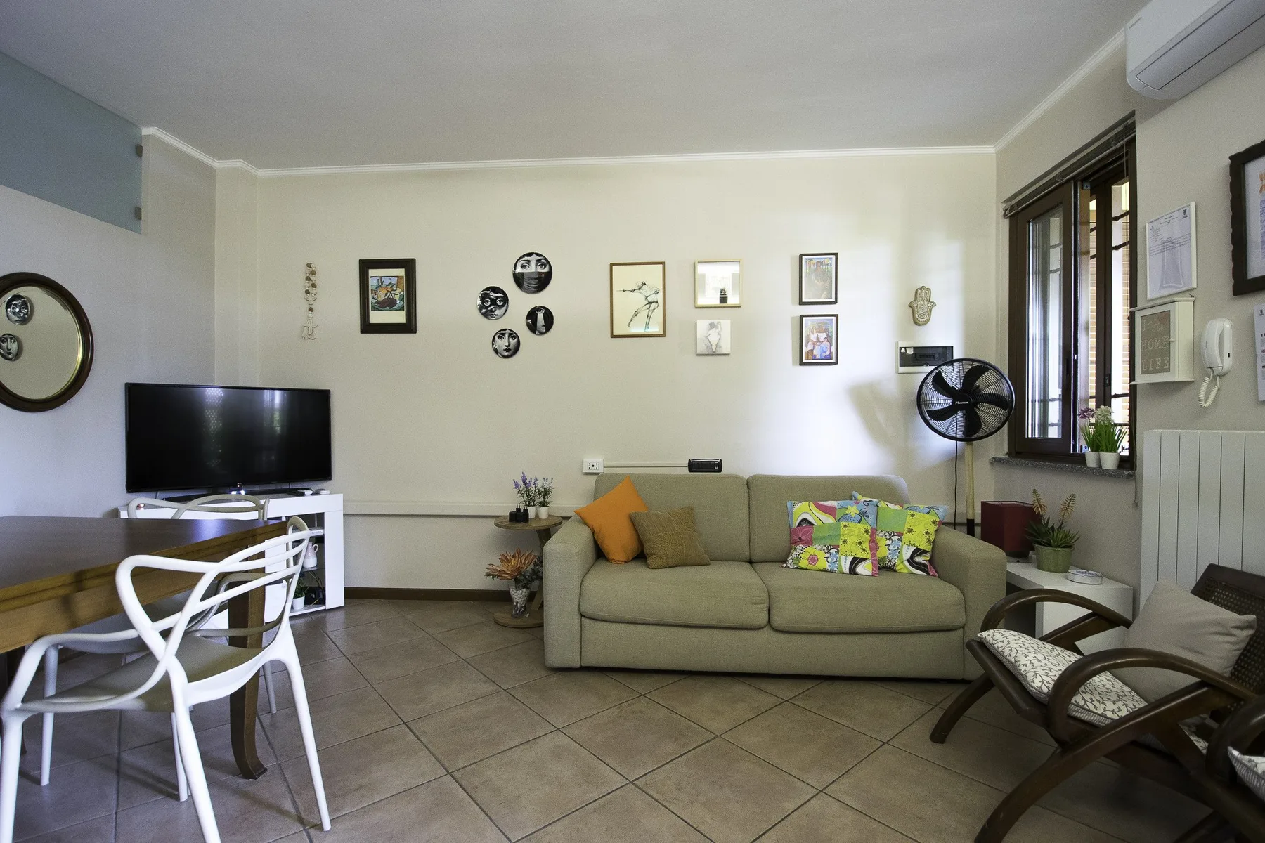 A living room with a sofa, television, and chairs.