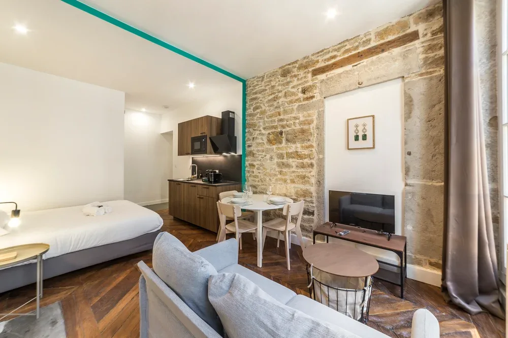 Una sala tipo estudio con cama, asientos, mesa de comedor y cocina pequeña.