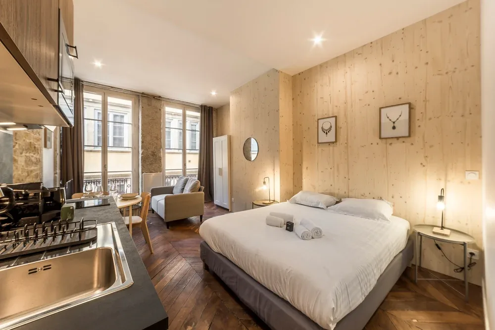 A bedroom with a large bed, bedside tables, and a small seating area.