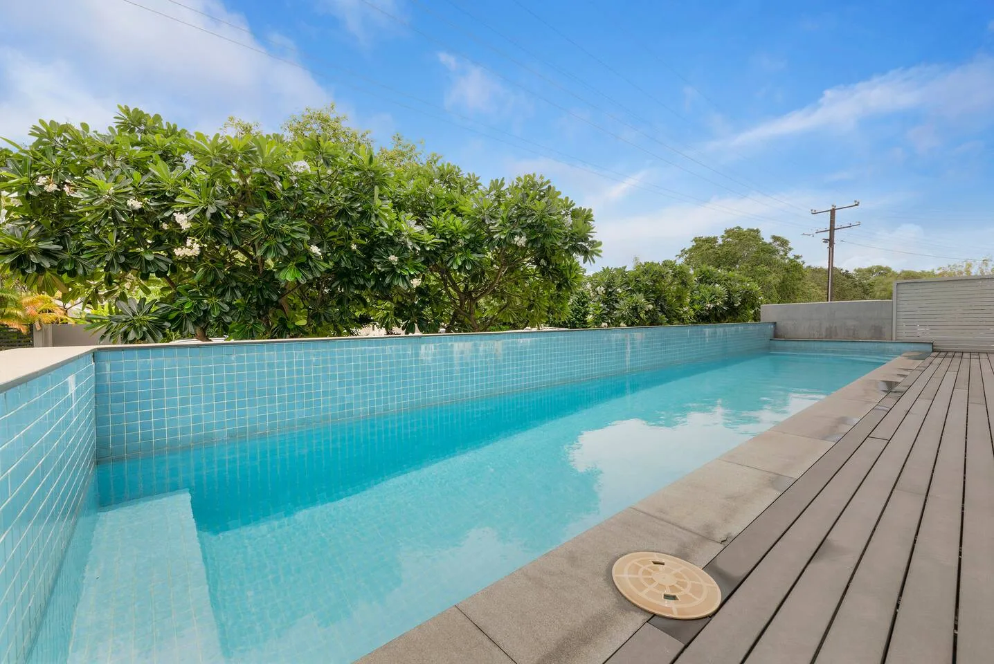 Una piscina al aire libre junto a árboles y una terraza de madera.