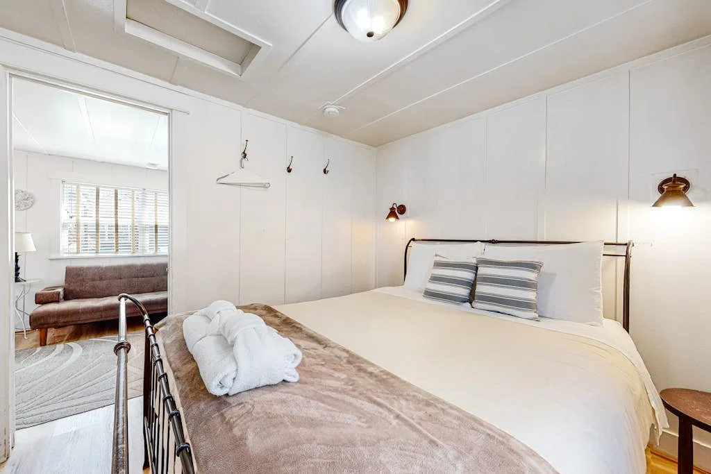 Un dormitorio luminoso con una cama grande y toallas dobladas sobre la colcha.