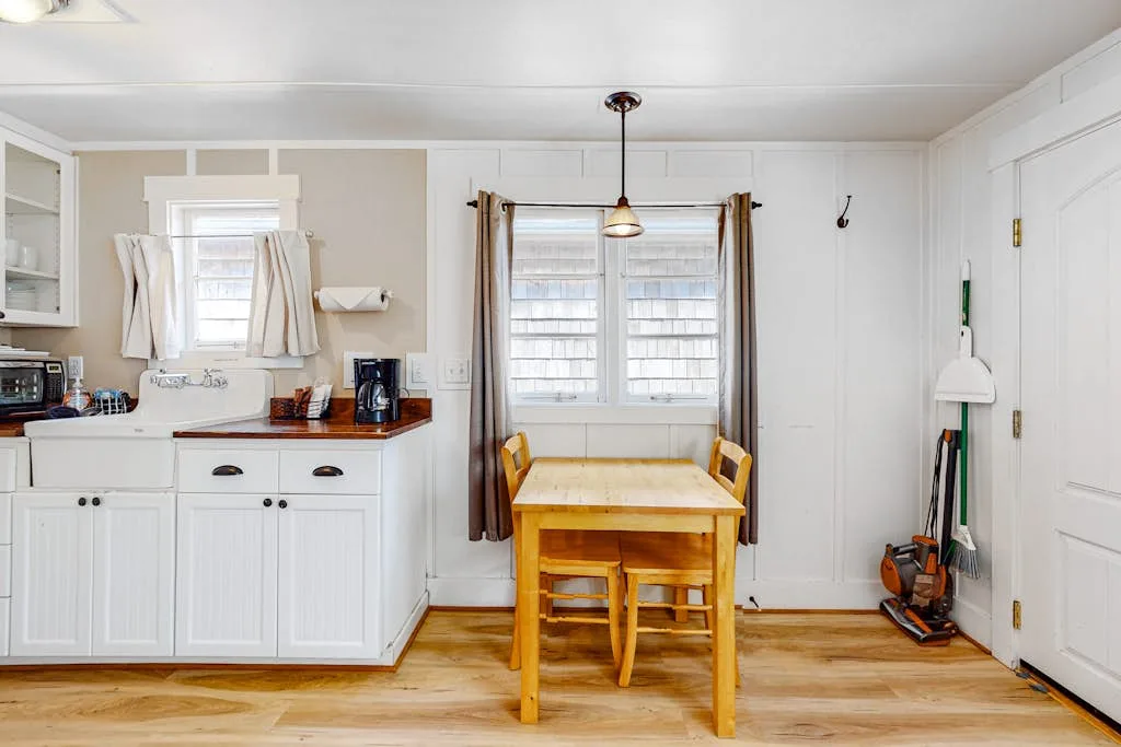 Un comedor luminoso con una mesa de madera junto a una cocina compacta.