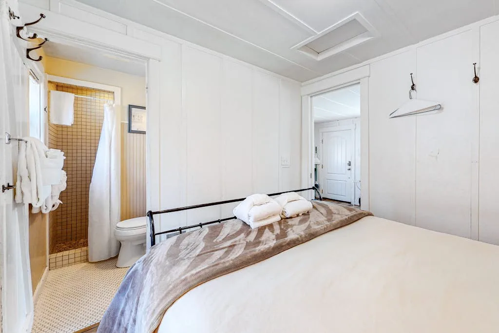 Un dormitorio con una cama en primer plano y una entrada al baño cerca.