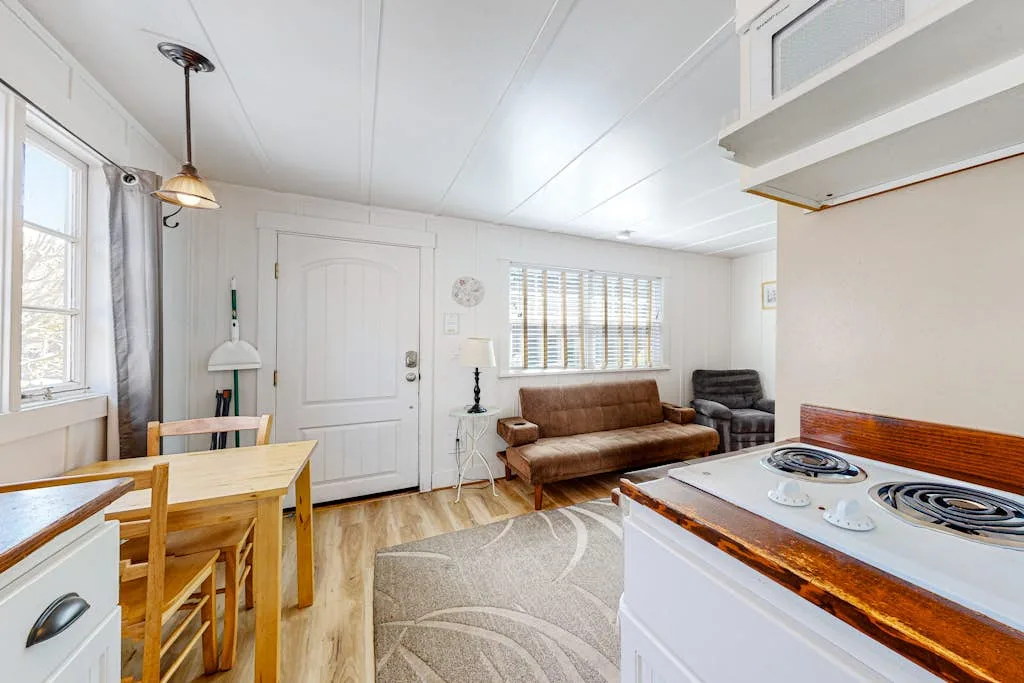 Una sala luminosa con una mesa de comedor y un sofá marrón.