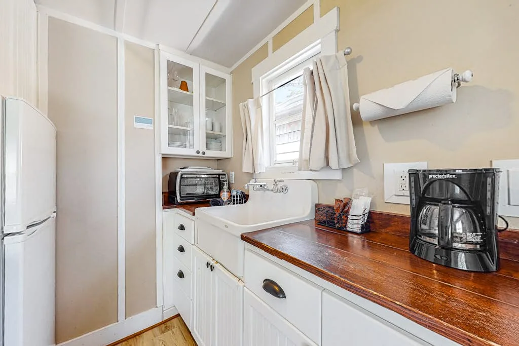 Una cocina pequeña con fregadero, encimera de madera y una ventana.