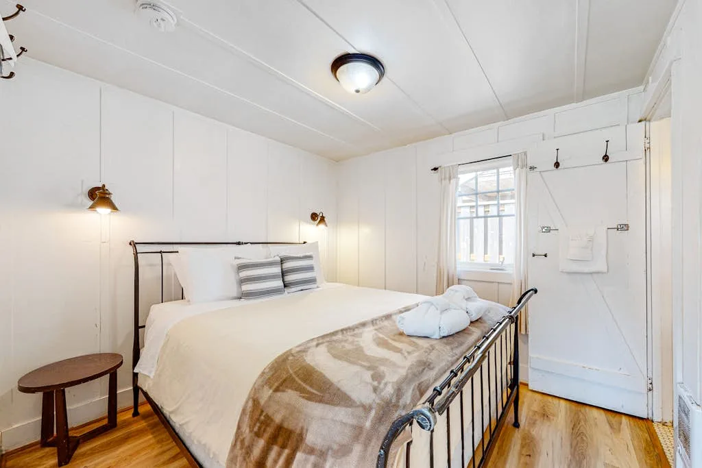 Un dormitorio luminoso con una cama bien hecha y una ventana junto a la puerta.