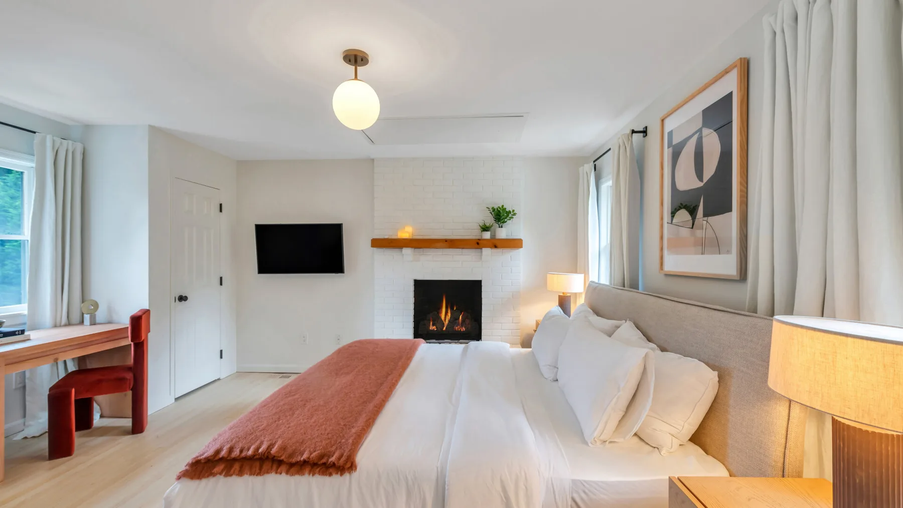 Un dormitorio luminoso con una cama bien tendida y una chimenea.