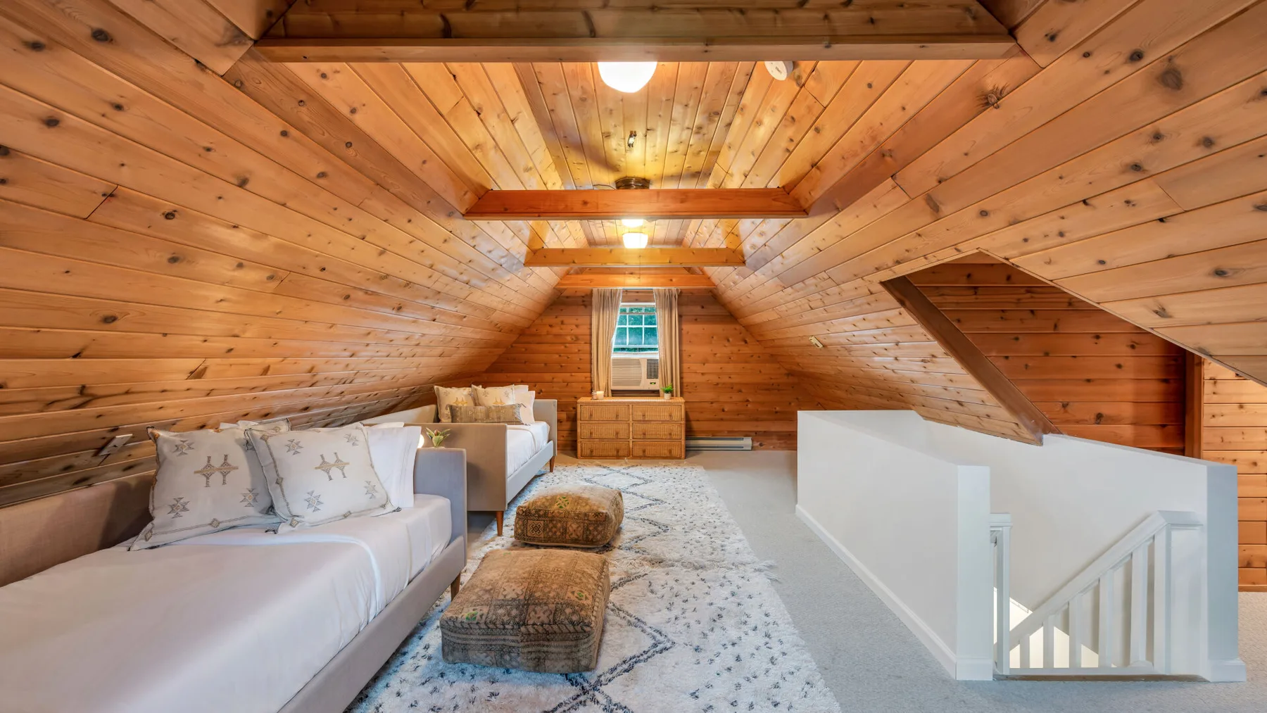 Una sala de estar abuhardillada con paredes de madera, asientos y una alfombra.