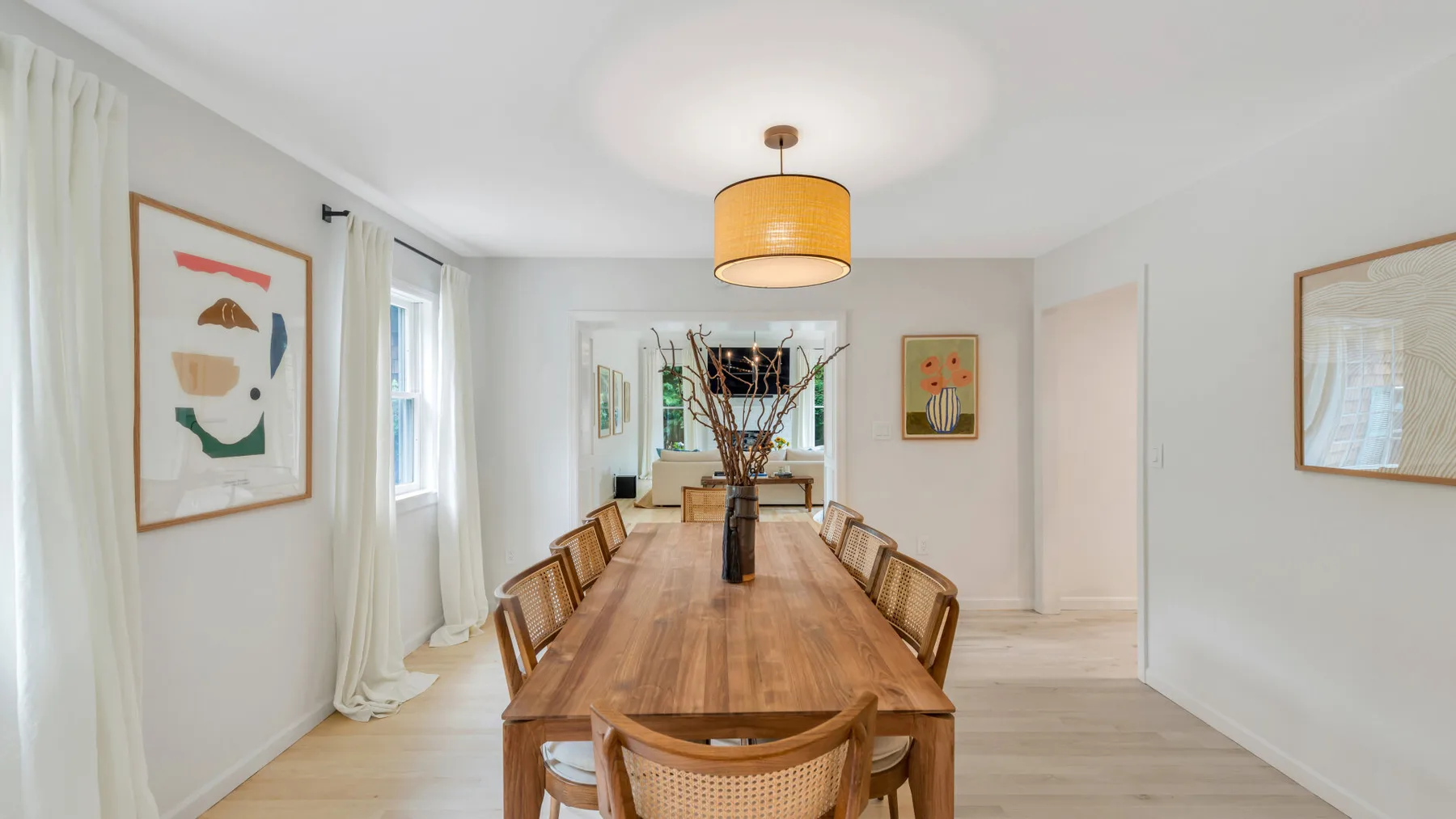 Comedor con una larga mesa de madera y sillas bajo una lámpara colgante.