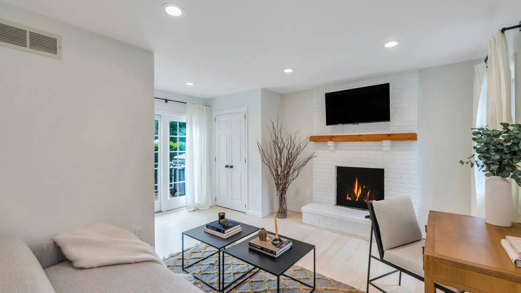Una sala luminosa con chimenea, televisor y asientos.