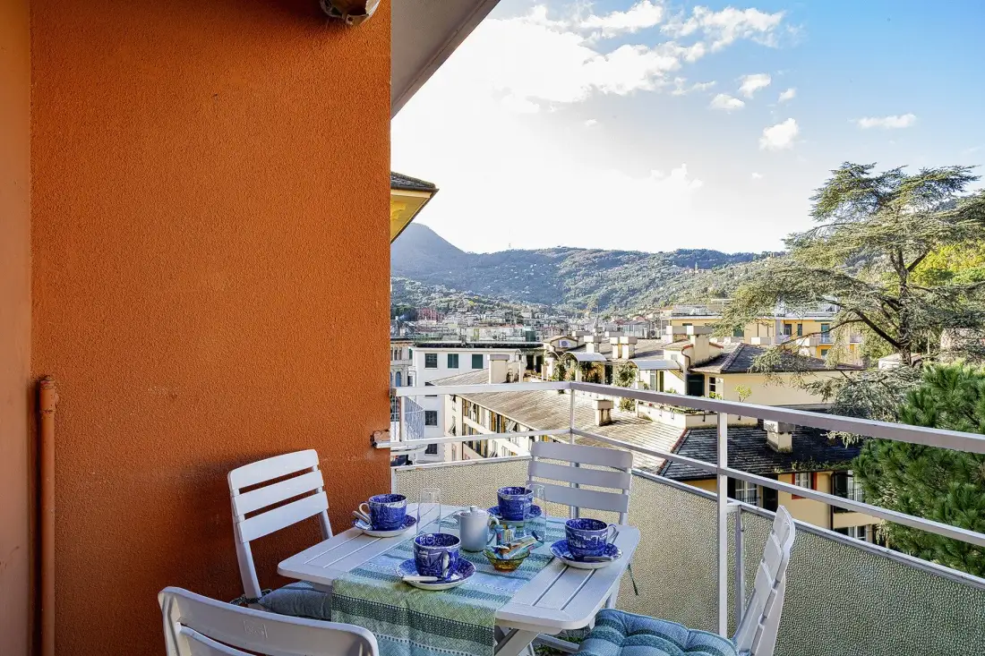 Un comedor en el balcón tiene vistas a una localidad y las colinas.