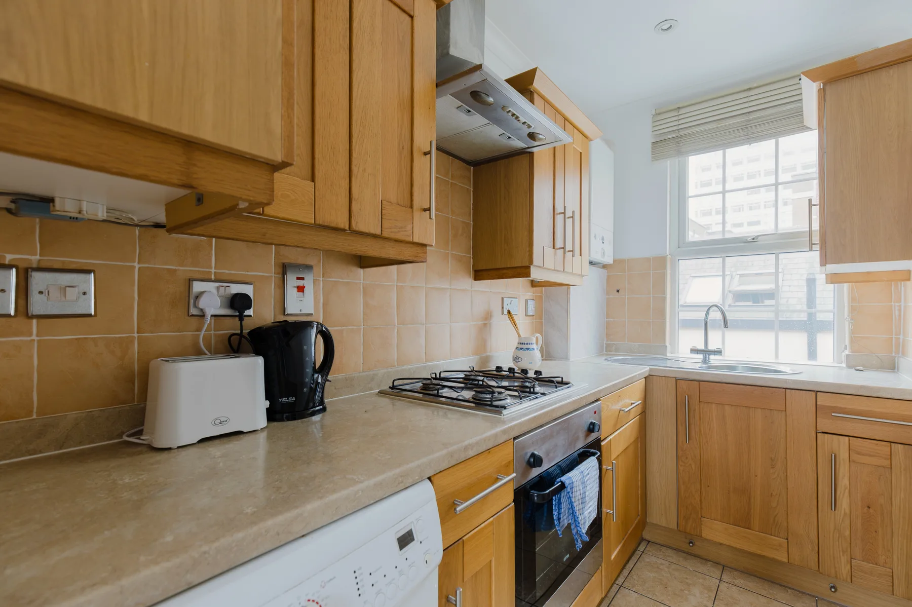 A kitchen with wooden cabinets, a countertop, and a window above the sink.