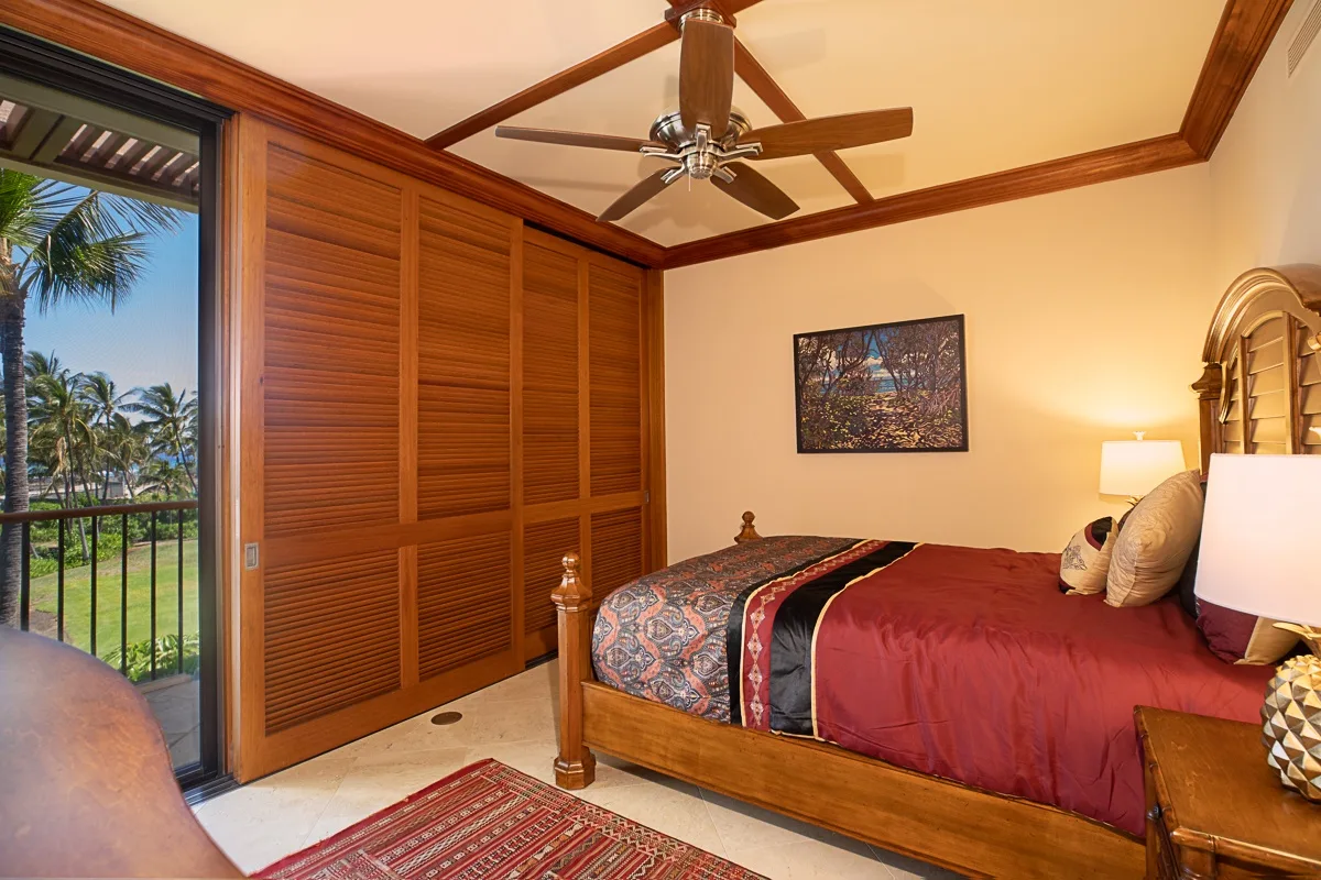 Un dormitorio con cama de madera, ropa de cama estampada y puertas de armario con persianas.